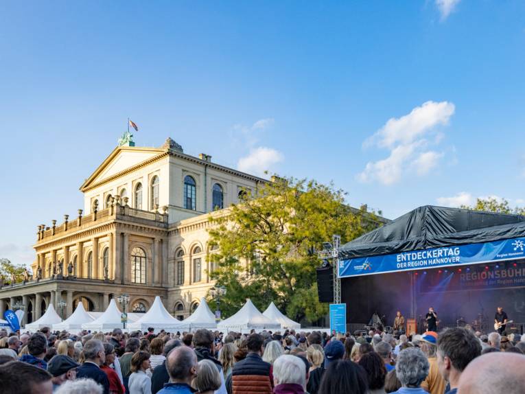Ein Platz mit vielen Menschen, die Oper Hannover und eine Bühne mit einer Band.
